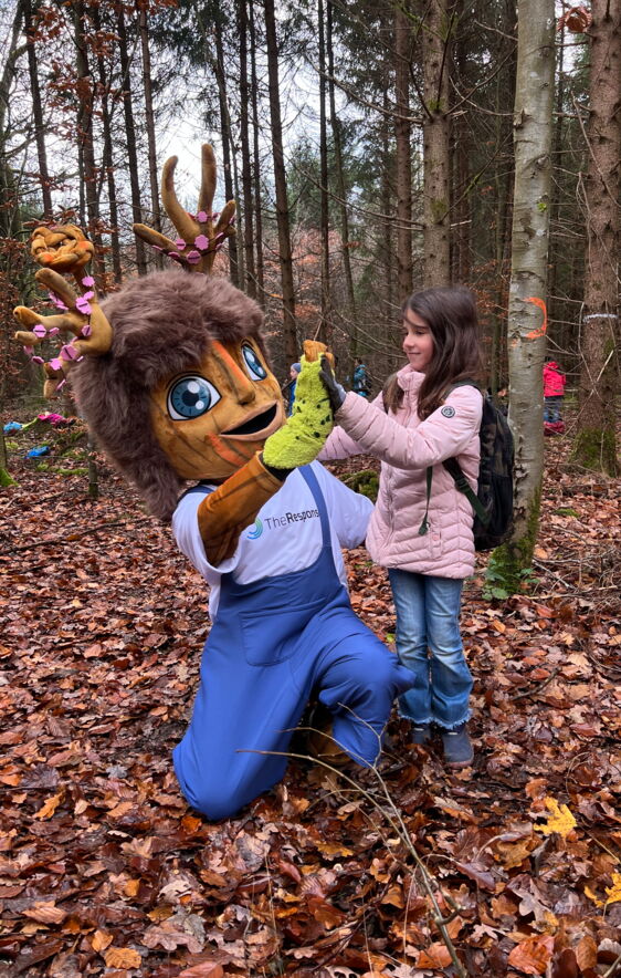 Maedchen pflanzt mit Rooty einen Baumsetzling bei Kids4Roots Pflanzaktion