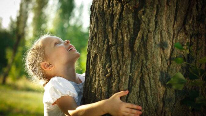 Maedchen umarmt einen Baum