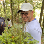 Mann mit Baumsetzling in der Hand bei Pflanzaktion