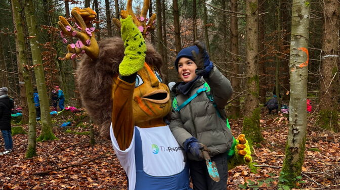 Junge pflanzt mit Rooty einen Baumsetzling bei Kids4Roots Pflanzaktion